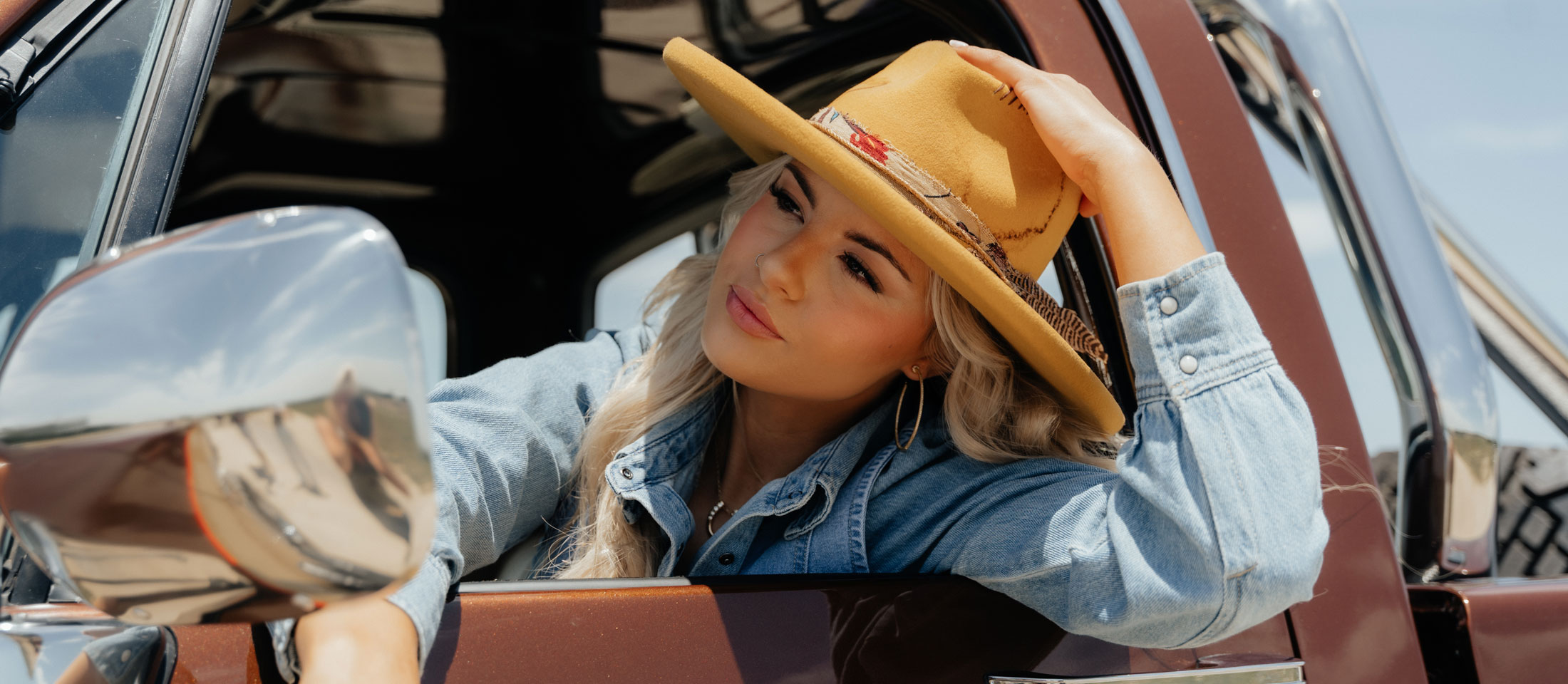 A woman wearing a cowboy hat while sitting in a pickup truck.